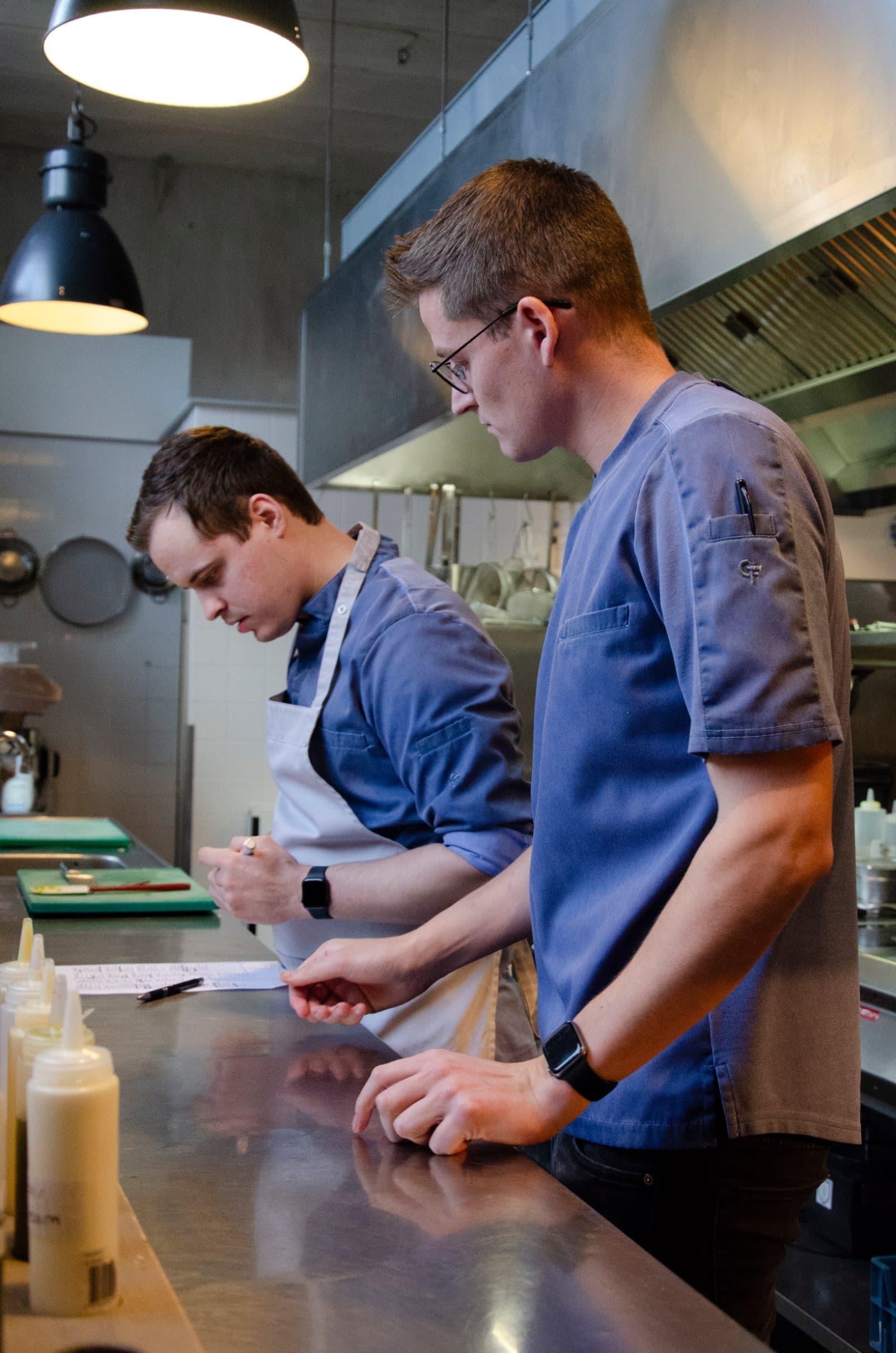 Twee chefs in blauwe Wastewear-koksbuizen aan de werkbank in een professionele keuken