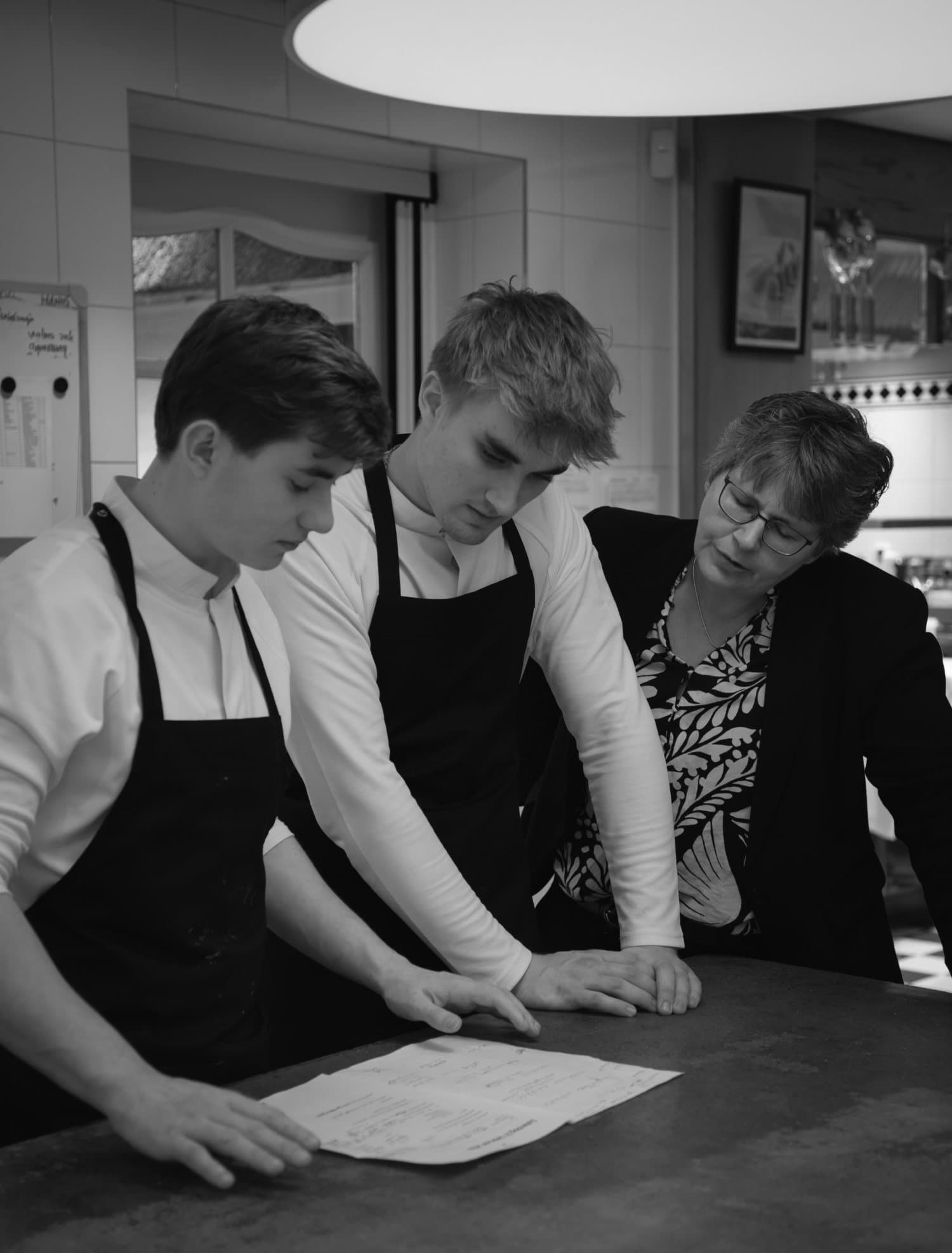 Twee jonge koks krijgen uitleg aan de werkbank in een professionele keuken