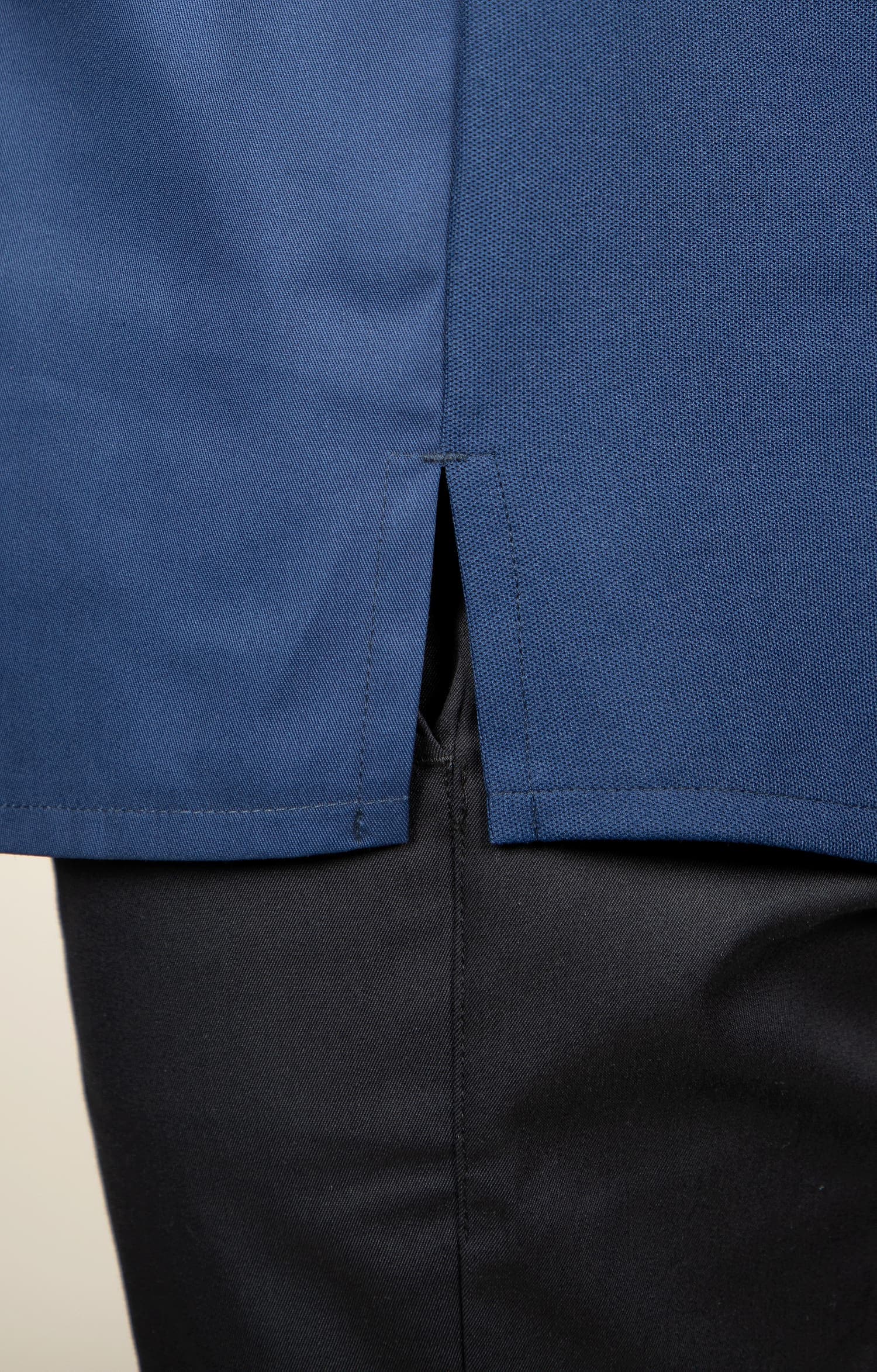 Detail van de verstevigde zijsplit en dubbele naden van een navyblauwe koksbuis